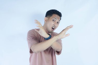 Pembe tişörtlü bir adam, tasvip etmeyen bir ifadeyle kollarını kavuşturur. Sanki 