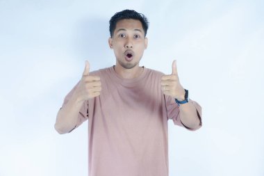 Pembe tişörtlü bir adam gülümser ve olumlu bir jest yapar ve onaylar. Açık mavi arka plan, onun neşeli ve kendinden emin tavırlarını vurguluyor..