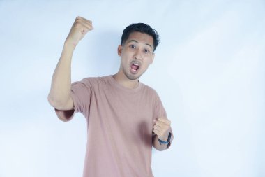 Pembe gömlekli bir adam kutlama jesti için iki elini de kaldırır, yüzü heyecan ve neşe içinde ışıldar. Açık mavi arka plan onun zafer ve coşkulu ifadesini vurguluyor..