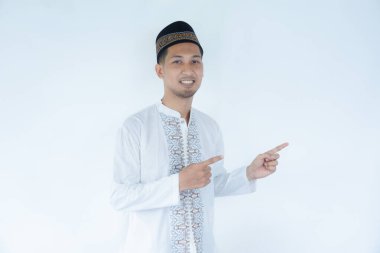 Moslem Asian man smiling and pointing both hands to the right side clipart