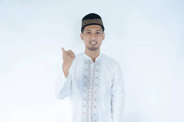 stock image Moslem Asian man smiling at the camera and pointing to the right side with his thumb