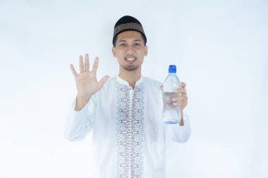 Moslem Asian man smiling and showing five fingers while holding a drinking water bottle clipart