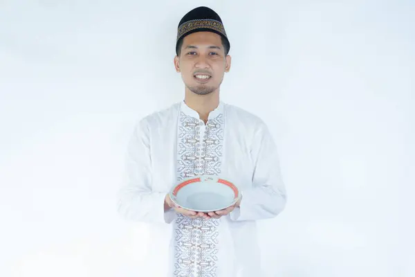 stock image Moslem Asian man smiling at the camera while holding empty dinning plate