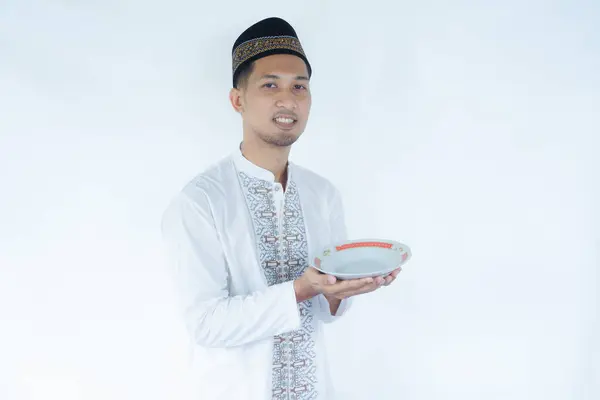 stock image Moslem Asian man smiling at the camera while holding empty dinning plate