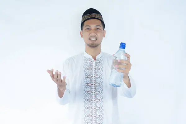 stock image Moslem Asian man smiling at the camera while holding a bottle of drinking water