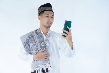 Moslem Asian man smiling happy when looking to his mobile phone clipart