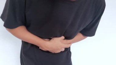 Genç adam gri arka plan boş alan izole midesi çok dokunaklı. Abdominal ağrı veya acı kavramı