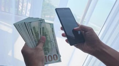 İş adamının el ele tutuşan telefonu ve mobil uygulamalara 100 dolarlık fatura, yatırım ve finans.