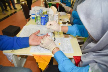 Doktor, parmak izinden kan tahlili yaptırıyor.