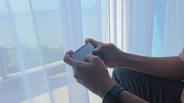Kapanış adamı evde oturup akıllı cep telefonuyla video oyunu oynuyor.