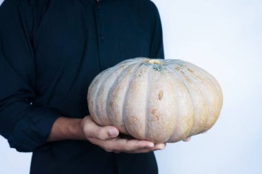 Elinde olgun, turuncu bir balkabağı tutan adam. Önden, yakın plan, beyaz arka plan izole edilmiş.