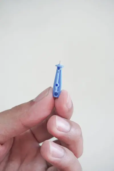 Beyaz arka planda izole kan glikoz kontrol etmek için insan işaret parmağına kan neşteri saplayan bir doktorun eli..