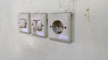 Genç yetişkin adam el ele tutuşuyor ve evdeki prizin prizine beyaz elektrik prizi takıyor. - Yakın çekim. Yan görünüm.