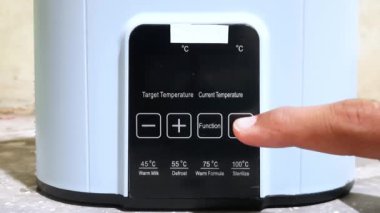 Bir adamın eli sterilizatörü çalıştırmak için düğmeye basıyor.