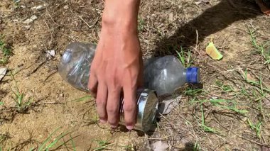 Çevresel bakım ve atık yönetimini gösteren plastik şişe ve teneke kutuları toplayan bir kişinin yakın çekimi. Toprak günü