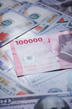 Endonezya rupia banknotlarının üst üste bindiği Amerikan dolarları yığını. Endonezya rupiasına karşı Amerikan dolarının enflasyonunun bir örneği