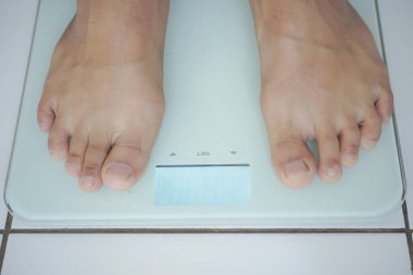 Erkek bacağı tartıya basıyor. Sağlıklı yaşam tarzı, yemek ve spor konsepti.