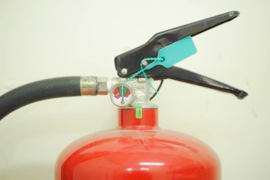 Basınç göstergesi ve güvenlik kilidi olan bir yangın söndürücünün yakın çekimi..