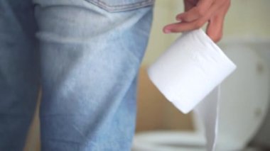 Mide ağrısı, midesi ağrıyan Asyalı hasta bir genç adam banyoda peçete rulosu tutuyor, tuvaletin yanında duruyor, çocuk ishalden muzdarip, midesi ağrıyor. Hijyen, sağlık konsepti.