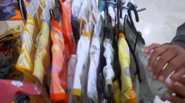 Yakın çekim anne bir şeyler satın alır ve bir çocuk mağazasından bebek ve çocuk kıyafetleri seçer. moda çocuk alışveriş konsepti