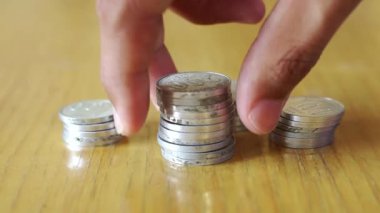 Bir adamın eli ahşap ofis masasına Endonezya Rupiah paraları istifliyor. Servet, tasarruf, finans ve para yönetimi kavramları. Yakın çekim görünümü.