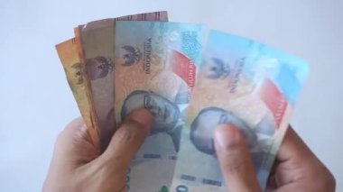 Endonezya rupia banknotlarını saymanın el hareketi, yakın plan.