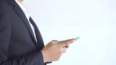 Takım elbiseli genç bir iş adamı mesajlaşmak için akıllı telefonu kullanıyor. Ofiste ya da kafede dokunmatik ekranlı cep telefonu kullanıyor. business, lifestyle, technology and Social media network concept