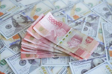Endonezya rupia banknotlarının üst üste bindiği Amerikan dolarları yığını. Endonezya rupiasına karşı Amerikan dolarının enflasyonunun bir örneği