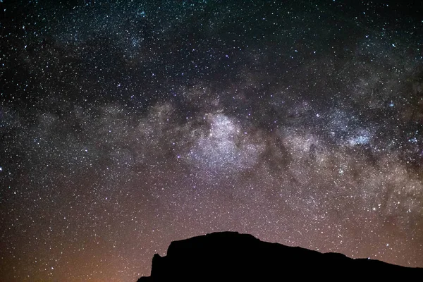 In the middle of the Teide, in a volcano in Tenerife, the Milky way bright in the night sky. There are lots of stars in the sky, and the milky way is in the top