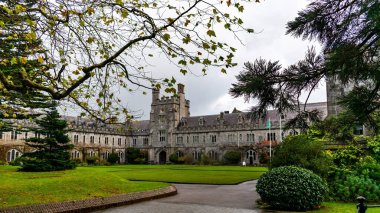 Serene Üniversitesi kampüsü yemyeşil ve tarihi binaları bulutlu bir gökyüzünün altında.