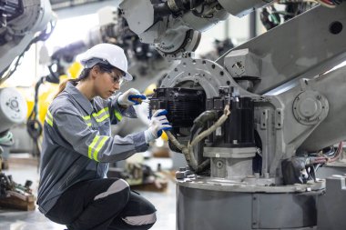 Robot teknisyenleri güvenlik onarımı için tornavida ve kerpetenle bileşenleri sıkılaştırıp gevşetiyorlar. Akım, voltaj, direnç, kapasite, dijital klemp ölçer ile sıcaklık ölçülüyor.