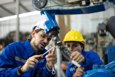 Robot teknisyenleri güvenlik onarımı için tornavida ve kerpetenle bileşenleri sıkılaştırıp gevşetiyorlar. Akım, voltaj, direnç, kapasite, dijital klemp ölçer ile sıcaklık ölçülüyor.