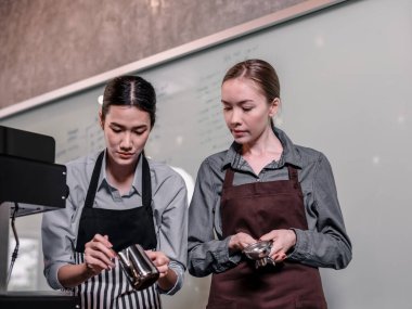 Genç yetişkin kahve makineleri menü yapmak için yetenekli baristlerle çalışır. Kahve makinesini kullanarak sıcak ve soğuk kahve yapmak. Üzerine süt köpüğü eklemek de dahil olmak üzere öğütme ve karıştırma deneyleri.