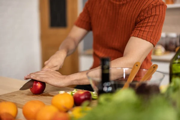 家庭的で健康的な男性は さまざまな果物を含む栄養価の高い食事を準備します ラップトップ上での料理ショーの後皮むきのマスター チョッピング 芸術的なスタイルでそれらを準備するために果物をスライス — ストック写真