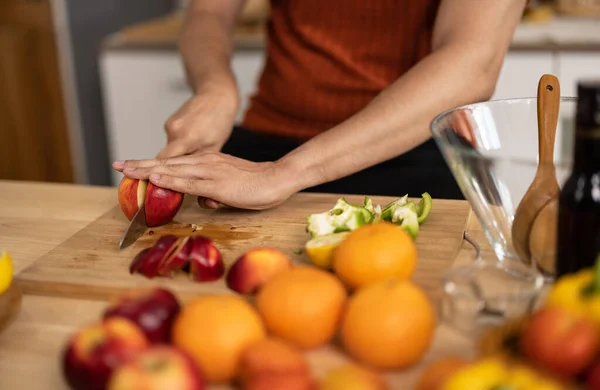 stock image A homely and healthy male prepares nutritious diet, including variety of fruits. Following cooking show on laptop Mastery of peeling, chopping, and slicing fruits to prepare them in artistic style.