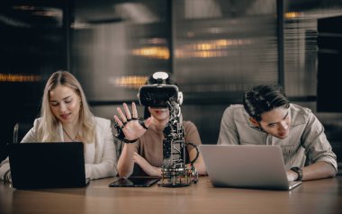 Üniversite öğrencileri eğitim robotlarıyla deney yapmak için araştırma ekibiyle işbirliği yapıyor. Sanal gerçeklik gözlüğü takmak, gerçek, etkileşimli durumları deneyimle ilişkilendirmeye yardımcı olur..