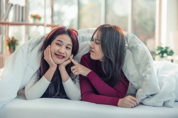 アジアのレズビアンのカップルは ベッドルームで毛布の下にお互いを見て 笑顔で リラックスして遊んでいます 一日の初めに行う必要がある日常的な活動があります — ストック写真