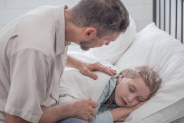 Babası kızını uyutmak için şarkı söylüyor, rahatlık, destek ve güvenlik sağlıyor. Hem fiziksel hem de duygusal ihtiyaçlarını karşılamaya odaklan. Çocuklar bazen uyuyormuş gibi yaparken mutlu davranırlar..