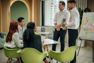 In multicultural workspace, innovative project manager present sustainable solar panel product, fostering collaboration and diversity among colleagues, aiming for efficient, renewable energy solution