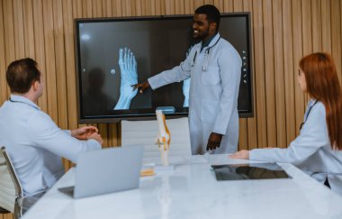 Cerrah, radyoloji uzmanı ve hastanın ayak bileği yaralanması vakası hakkında çok kültürlü bir toplantı. En etkili, kesin tedavi planı ve prosedürü için MRI taramalarını inceler ve analiz ederler.