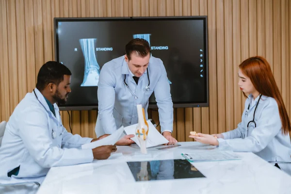 外科医と患者の足首の怪我についての放射線科医の間の多文化委員会の議論 彼らは 最も効果的で正確な治療計画と手順のためのMriスキャンを調べ 分析します — ストック写真