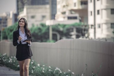 Kararlı ve kendine güvenen bir yönetici kadın, tabletini elinde tutarak olağanüstü liderlik, bağlılık ve stratejik düşünce örneği göstererek örgütü gururla yönetiyor..