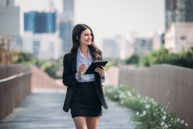 Kararlı ve kendine güvenen bir yönetici kadın, tabletini elinde tutarak olağanüstü liderlik, bağlılık ve stratejik düşünce örneği göstererek örgütü gururla yönetiyor..