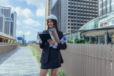 Yetenekli kadın mimar, Skytrain ve çevresindeki inşaat alanlarını titizlikle inceliyor. Planları ve mimari yapıları karşılaştırıyor. Proje onayı için hassas hesaplamalar uygulanıyor.