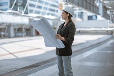 Yetenekli kadın mimar, Skytrain ve çevresindeki inşaat alanlarını titizlikle inceliyor. Planları ve mimari yapıları karşılaştırıyor. Proje onayı için hassas hesaplamalar uygulanıyor.