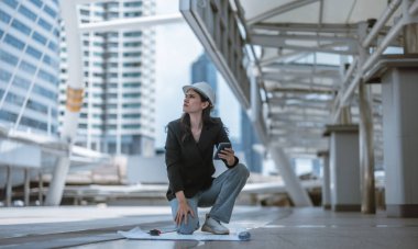 Yetenekli kadın mimar, Skytrain ve çevresindeki inşaat alanlarını titizlikle inceliyor. Planları ve mimari yapıları karşılaştırıyor. Proje onayı için hassas hesaplamalar uygulanıyor.