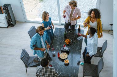 Arkadaşların canlı, çok kültürlü bir araya gelişi, kahkahalar, çeşitli hikayeler, heyecan verici etkileşimler. Birliktelik, kaynaşma, kutlama, müziğin, dansın, sohbetin neşeli bir atmosfer yarattığı yer.