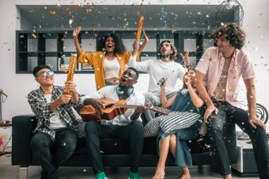 Arkadaşların canlı, çok kültürlü bir araya gelişi, kahkahalar, çeşitli hikayeler, heyecan verici etkileşimler. Birliktelik, kaynaşma, kutlama, müziğin, dansın, sohbetin neşeli bir atmosfer yarattığı yer.