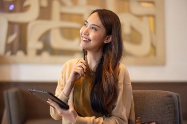 Asyalı kadın yönetici bir kahve dükkanında bulunurken kapsamlı bir analiz yaparak olası bir yatırım projesi için uzaktan onay verdi. Genişleme için dikkatlice tasarlanmış stratejik karar.