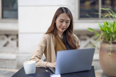 Asyalı kadın yönetici bir kahve dükkanında bulunurken kapsamlı bir analiz yaparak olası bir yatırım projesi için uzaktan onay verdi. Genişleme için dikkatlice tasarlanmış stratejik karar.